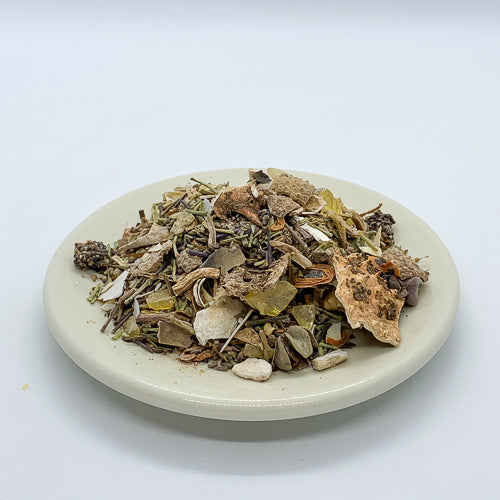 Encens Fasoukh marocain traditionnel dans un encensoir en laiton, avec lavande, sauge et harmal en arrière-plan.